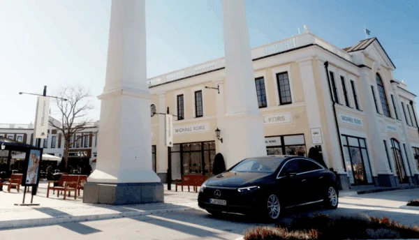 A black Driversline sedan in front of the columned entrance of the Designer Outlet Neumünster