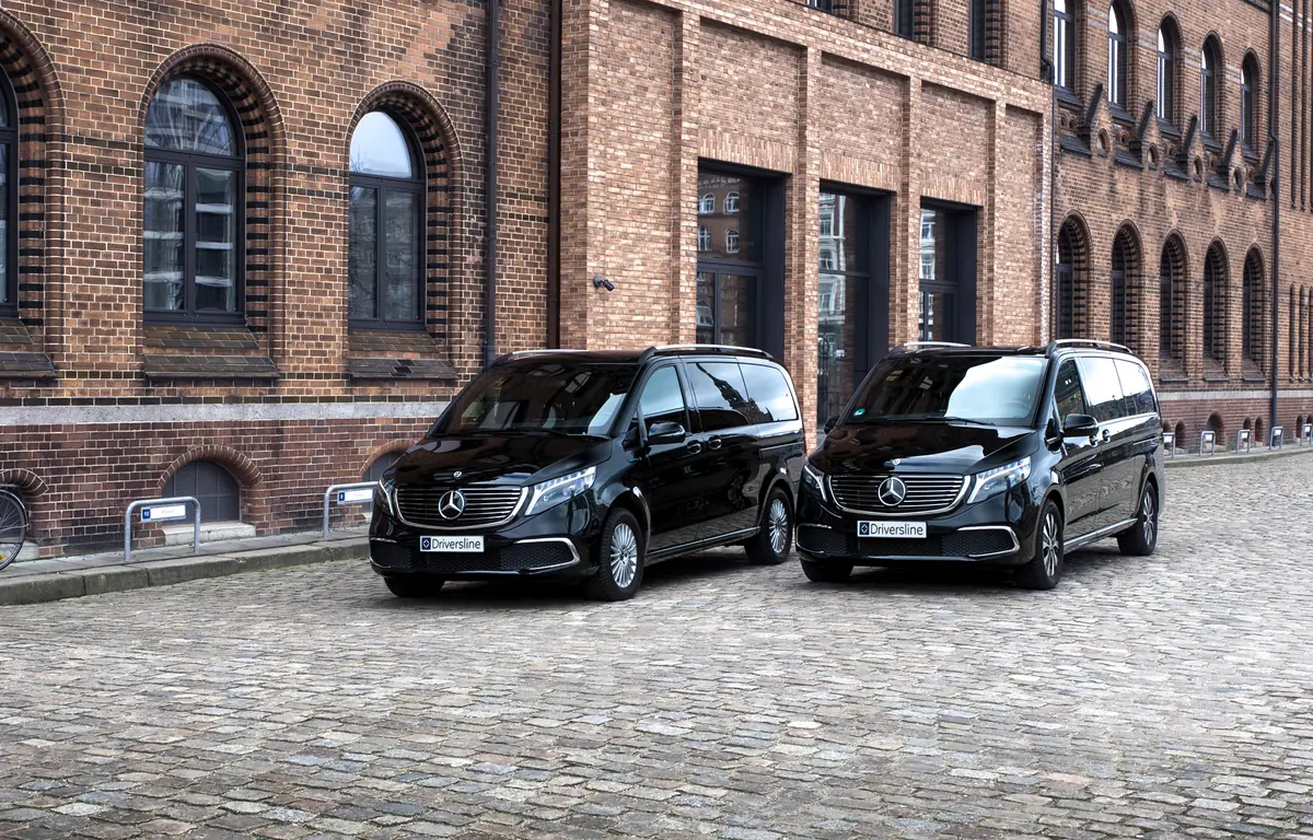 Two black electric Mercedes-Benz EQV with Driversline plates on cobblestones in front of a Hamburg brick facade