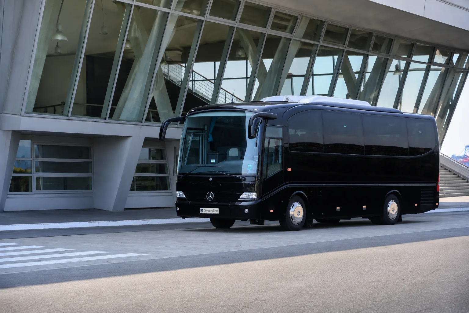 Schwarzer Reisebus der Driversline Flotte vor einem Flughafenterminal