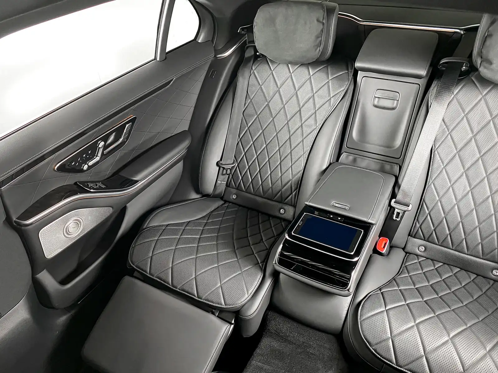 The rear seats of a sedan with quilted leather, its own centre console and a control screen