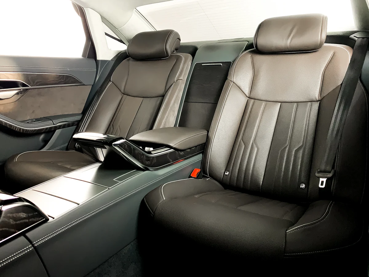 Rear of a sedan with two individual seats in light brown leather and the centre armrest folded down