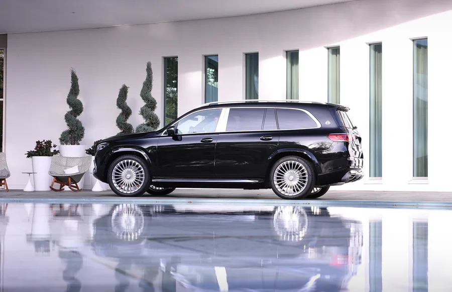 Black Mercedes-Maybach GLS in full side view in front of a light building, reflected in water