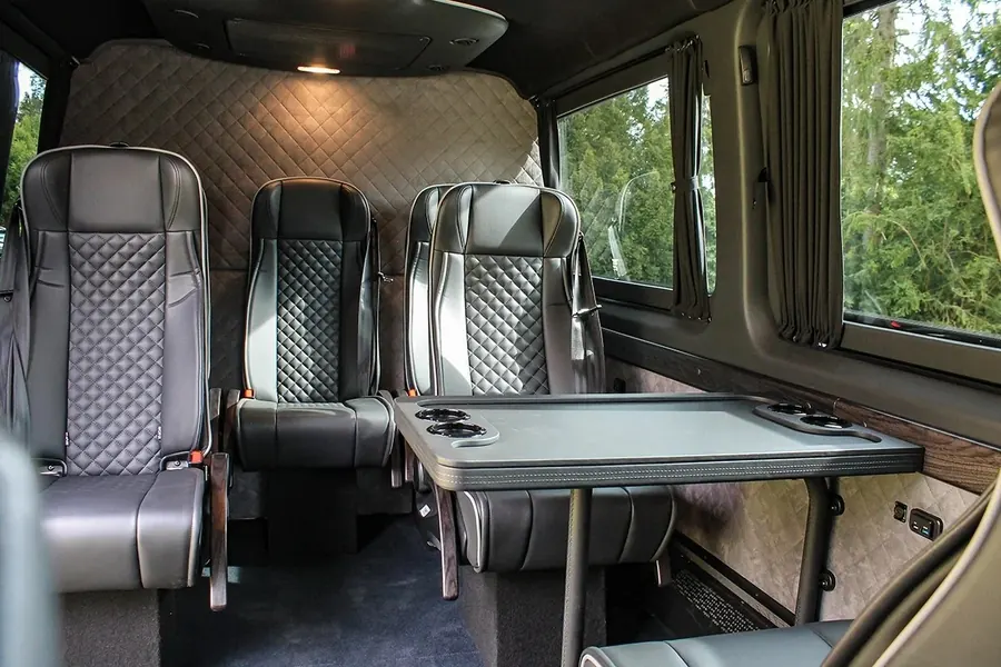Seating group in the Mercedes-Benz Sprinter VIP with the table folded out and curtains
