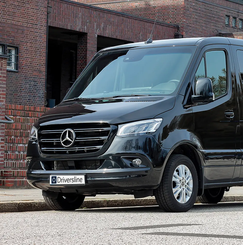 Front of a black Mercedes-Benz VIP Sprinter with star, radiator grille and number plate with the Driversline lettering