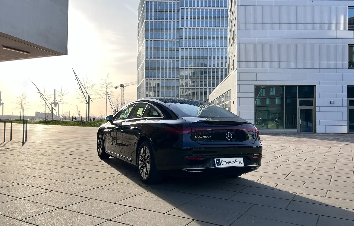 A black Mercedes-Benz S-Class at the forecourt of a modern office building