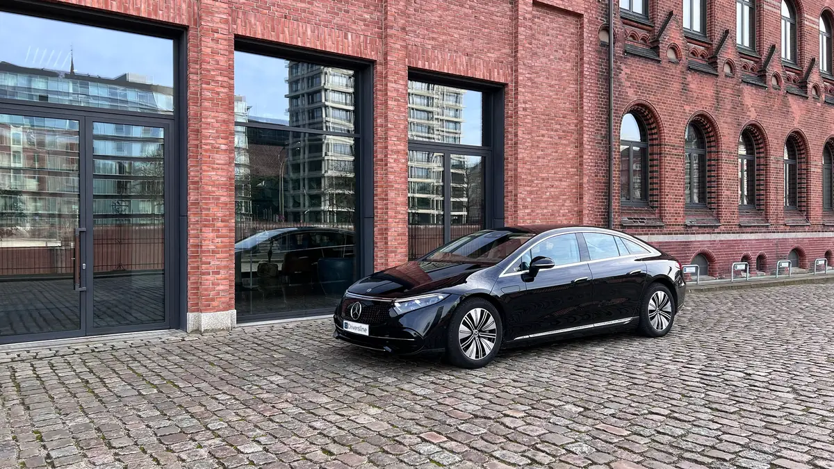 A black Driversline sedan on cobblestones in front of a Hamburg brick facade with office windows