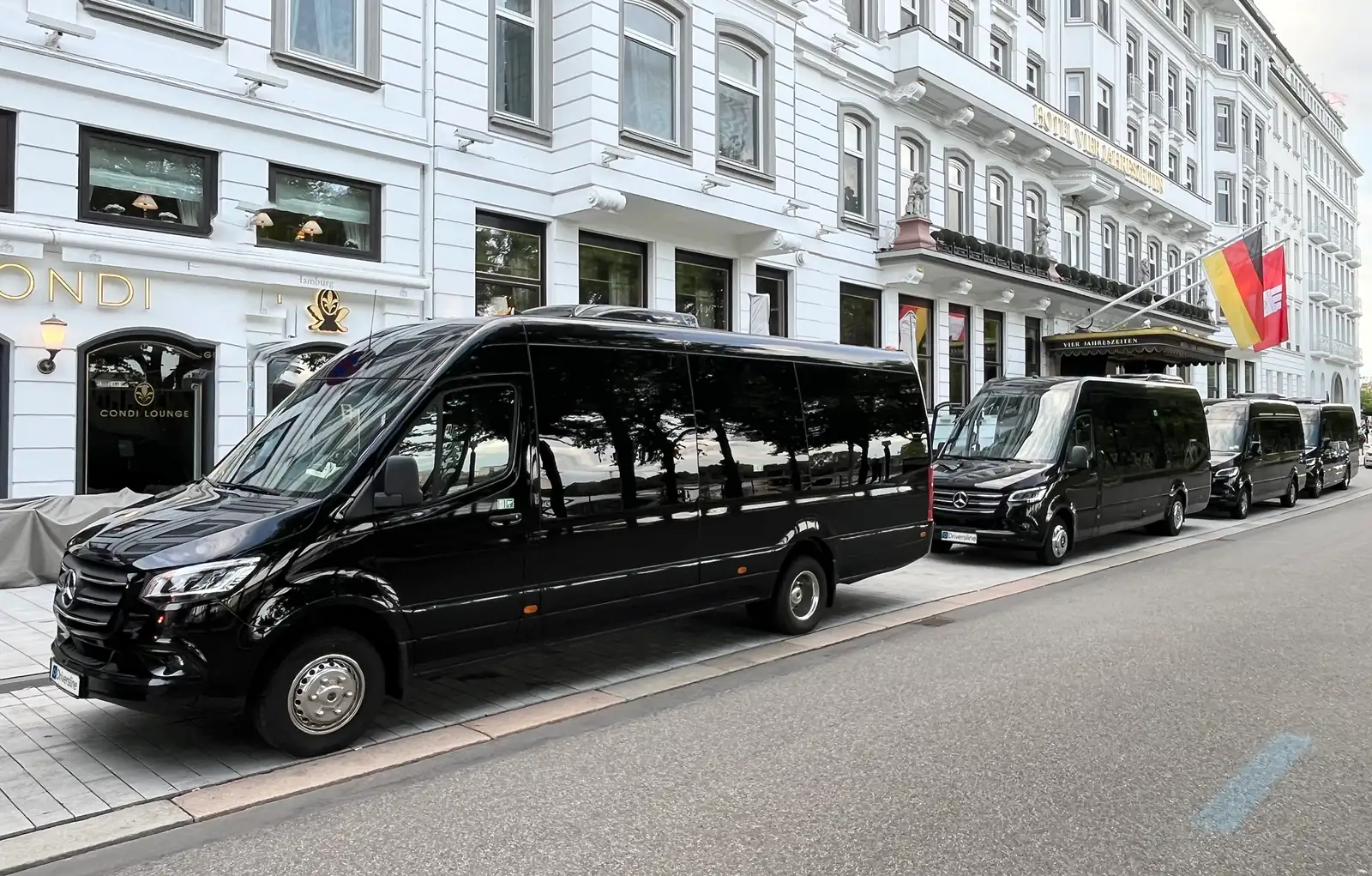 Four black Driversline VIP Sprinters in a row at the roadside outside a hotel