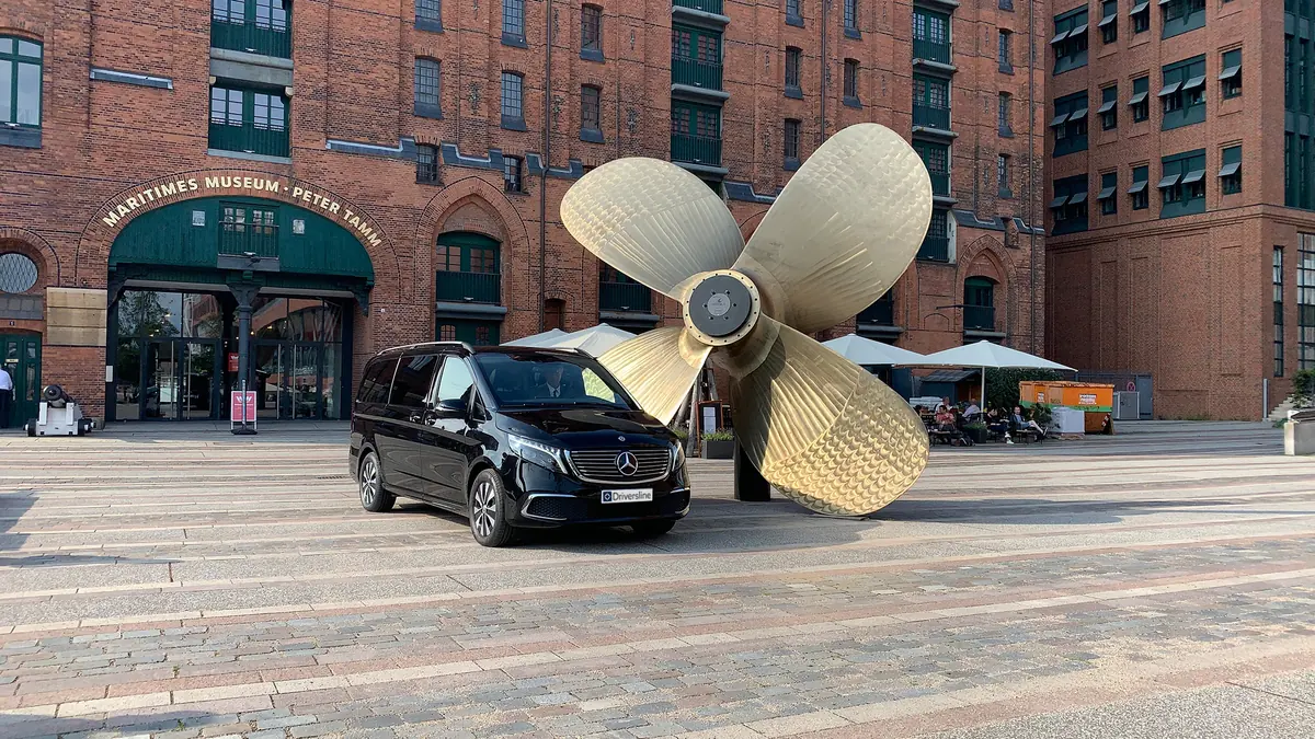 A black Mercedes-Benz van in front of the golden ship's propeller at the International Maritime Museum in Hamburg