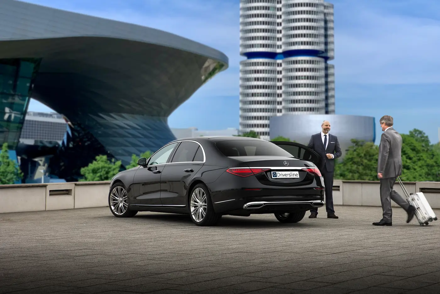 Chauffeur an der geöffneten Fondtür einer schwarzen Mercedes-Benz S-Klasse vor der BMW Welt in München, ein Fahrgast mit Koffer kommt hinzu
