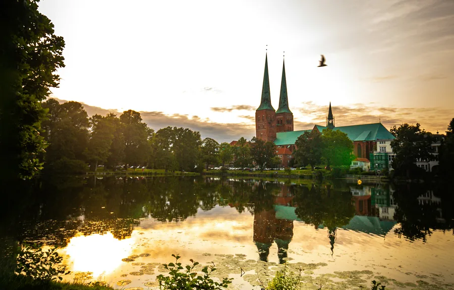 Lübeck Cathedral with its twin towers in the evening light, reflected in the Mühlenteich